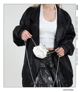 Schicke weiße Ledertasche mit Schleifen und Silberkette an einem modischen Model