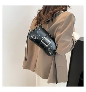Détail du sac en cuir brillant noir avec rivets argentés et boucles en métal sur la bandoulière