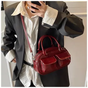 Close-up of red glossy vintage underarm bag featuring decorative pockets and metal chains