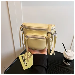 Détail du sac selle en cuir crème avec boucles argentées et bandoulière réglable