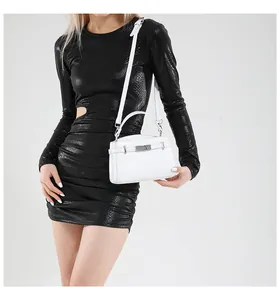 Close-up of white leather handbag with silver metal twist lock on a black dress background