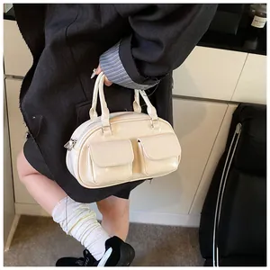 Close-up of cream glossy patent leather bag with two front pockets and zipper detail