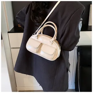 Close-up of beige glossy faux leather shoulder bag with two front pockets on a model