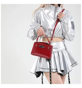Detail of red glossy leather handbag with silver metallic buckle and adjustable strap