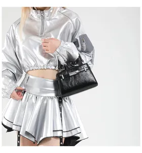 Model styling a large black leather handbag with metallic hardware for 2025 summer