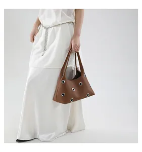 Detailaufnahme der braunen Ledertasche mit modernen silbernen Metallösen-Verzierungen
