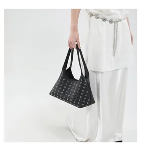 Detail der schwarzen Punk-Handtasche mit silbernen Ösen am Modell für einen Fashion-Look
