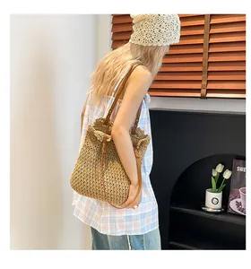 Detail of woven straw tote bag featuring brown leather shoulder straps and metal rivets