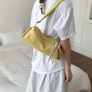 Minimalist yellow canvas cylinder crossbody bag with decorative rope details