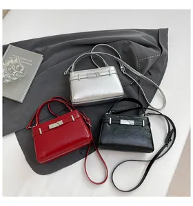 Detailed view of silver, red, and black leather handbags with metallic lock and shoulder straps