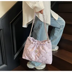 Détail du sac seau matelassé lilas avec étoile argentée et bandoulière sur modèle