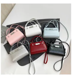 Close-up of mini leather handbags in pink, white, blue, and black with metal buckles