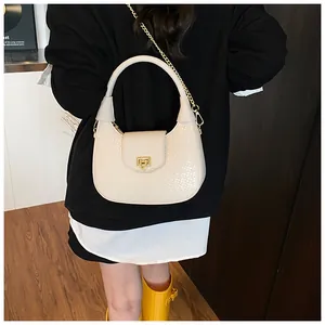 Detail of cream woven hobo bag with gold chain strap and metallic clasp closure