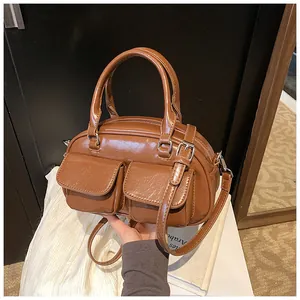 Detail of caramel glossy leather bag with dual front pockets and top handle