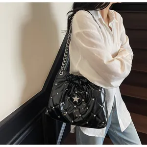 Détail du sac seau matelassé noir avec rivet en étoile argentée et bandoulière chaîne