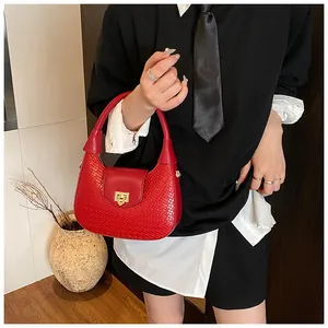 Close-up of a red crocodile pattern handbag with a golden metal lock and woven texture
