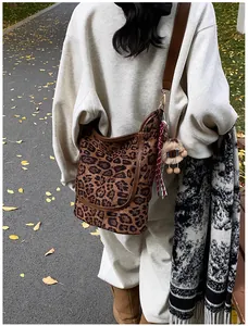 Leopard print hobo bag featuring brown leather trim and a plush bear charm on a grey sweatshirt