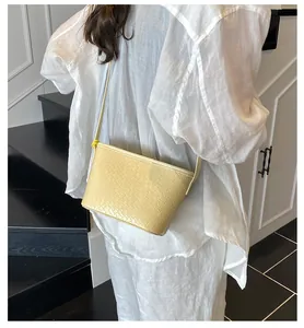 Detail showing pale yellow woven texture of a stylish crossbody bag on a model