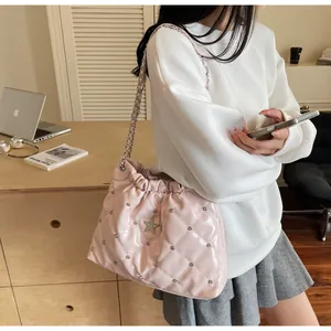 Sac seau matelassé rose avec bandoulière chaîne et détail étoile porté par mannequin