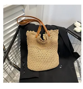 Close-up of woven hollow pattern and brown leather handle on handmade straw tote bag
