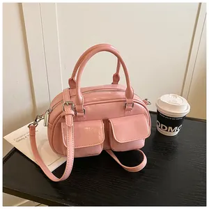 Macro view of pink patent leather bag showing double buckled front pockets and metallic gloss
