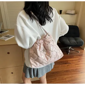 Détail du sac seau rose matelassé avec rivets étoiles argentés et bandoulière chaîne
