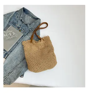 Detailed top view of a woven straw bag with scalloped edges and brown leather straps