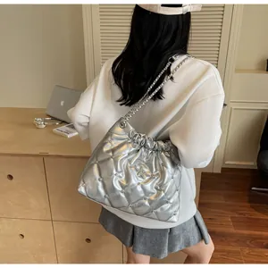 Détail du sac seau matelassé argenté avec clous et breloque étoile porté sur l'épaule