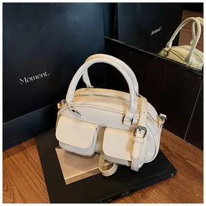 Detailed view of the off-white glossy faux leather handbag with functional front pockets