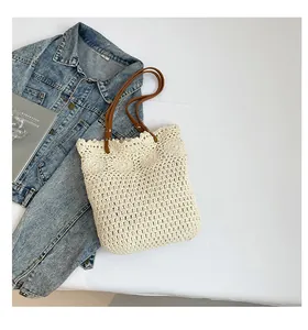 Detail of cream woven tote bag featuring decorative lace trim and brown leather handles