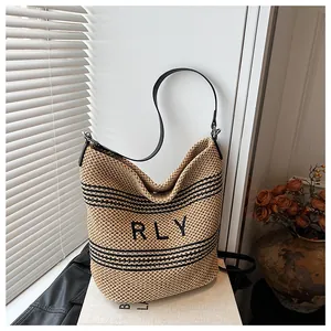 Dettaglio della borsa tote in rafia con ricamo RLY nero e tracolla in pelle nera