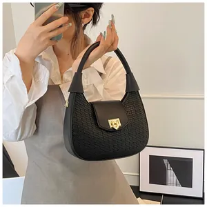 Close-up of woven black crescent handbag with elegant gold metal twist lock buckle detail