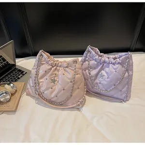 Détail de sacs seaux matelassés rose et violet avec étoiles et bandoulière chaîne