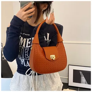 Detail of orange woven crescent bag with gold heart-shaped lock shown in a mirror selfie