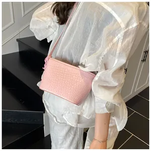Detailed view of pink woven texture crossbody bag with knot shoulder strap on model