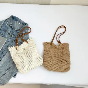 Handwoven straw tote bag with brown leather handles and decorative floral patterns
