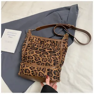 Macro view of leopard print fabric texture and adjustable brown leather shoulder strap