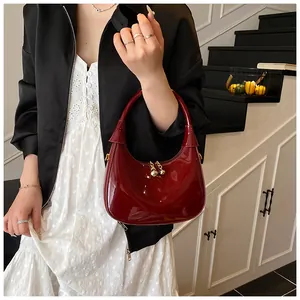 Detail of burgundy patent leather crescent bag featuring a golden ball clasp closure