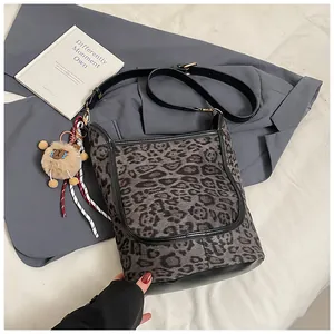 Detail of leopard print tote bag featuring a cute sheep plush charm and black leather strap