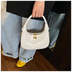 Detailed view of white glossy half-moon handbag with gold ball zipper and smooth leather texture