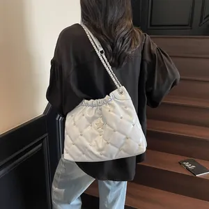 Sac seau matelassé bleu clair avec logo étoile et rivets porté par un mannequin