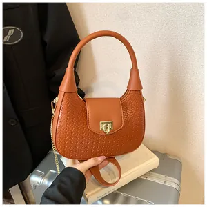 Close-up of brown woven texture handbag with gold metal clasp and chain strap detail