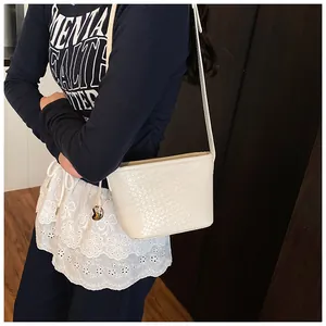 Detailed view of a white woven bucket bag featuring a polished heart-shaped metal charm