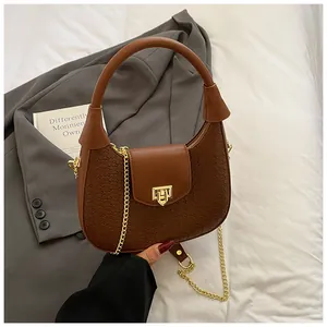 Detail of a brown woven hobo bag with a gold metal chain strap on a blazer background