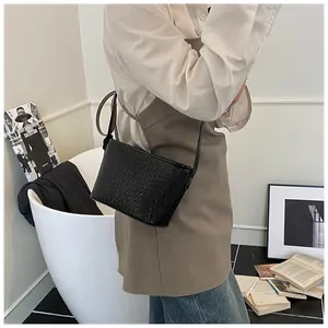 Detail of black woven shoulder bag with intricate Intrecciato texture and slim strap