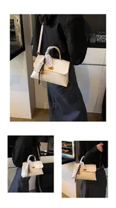 Detail view of cream-white leather handbag with polka dot scarf and golden metal twist lock