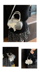 Detail of silver metallic mini bowling bag featuring a lace bow and pearl heart charm