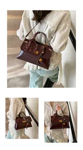 Detail of dark red glossy faux leather bag with silk scarf handle and golden bell charm