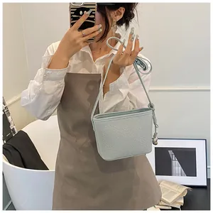 Detail of light blue woven bucket bag with silver heart pendant and crossbody strap