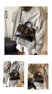 Detailed close-up of glossy black handbag featuring gold twist lock and polka dot scarf